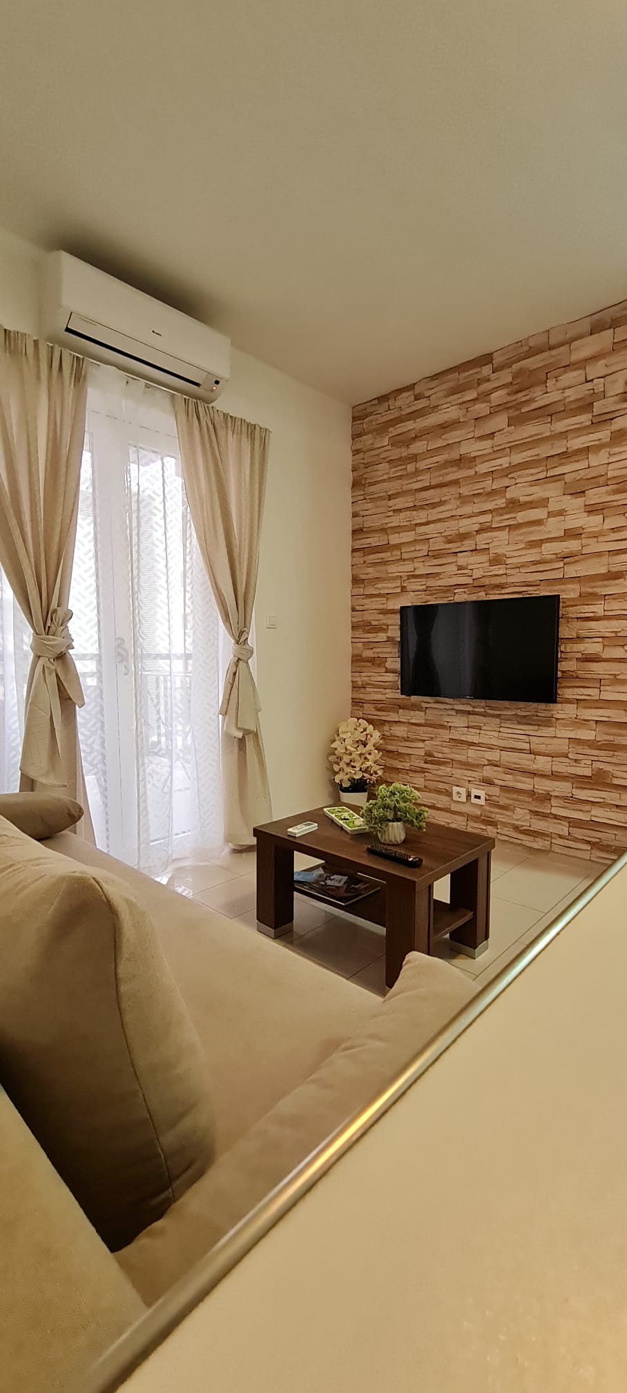 Living room with stone TV wall and balcony